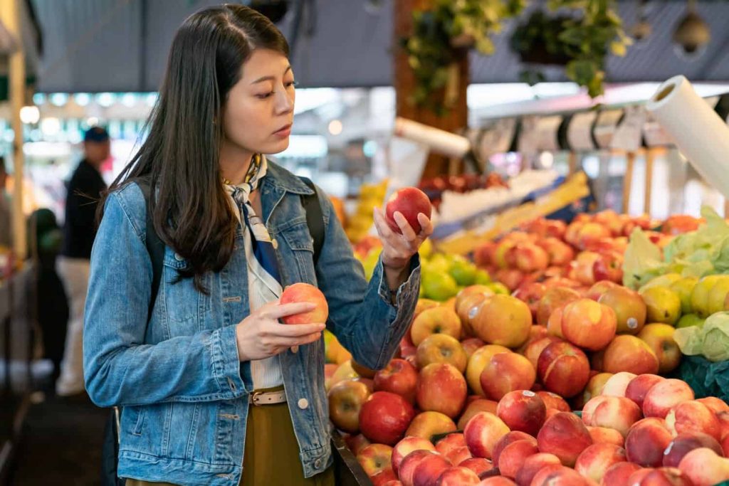 A Japanese woman looking at fresh produce that passed Japan’s pesticide standards.